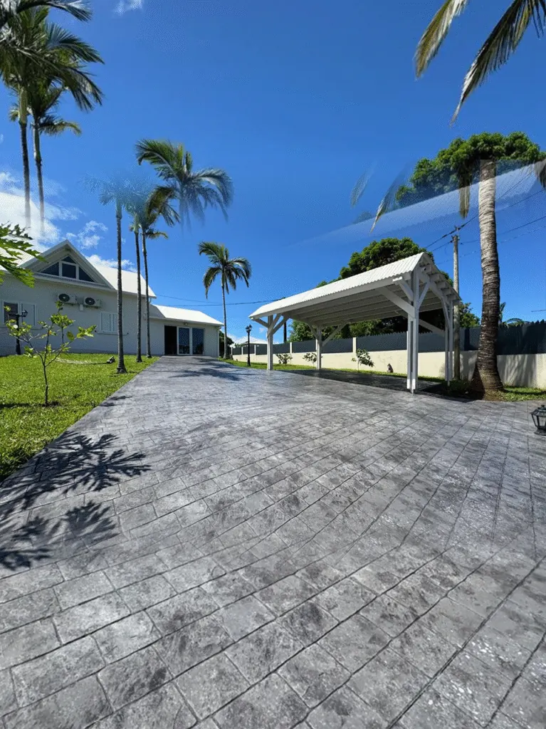 Allée en béton imprimé menant à un carport, sous les palmiers
