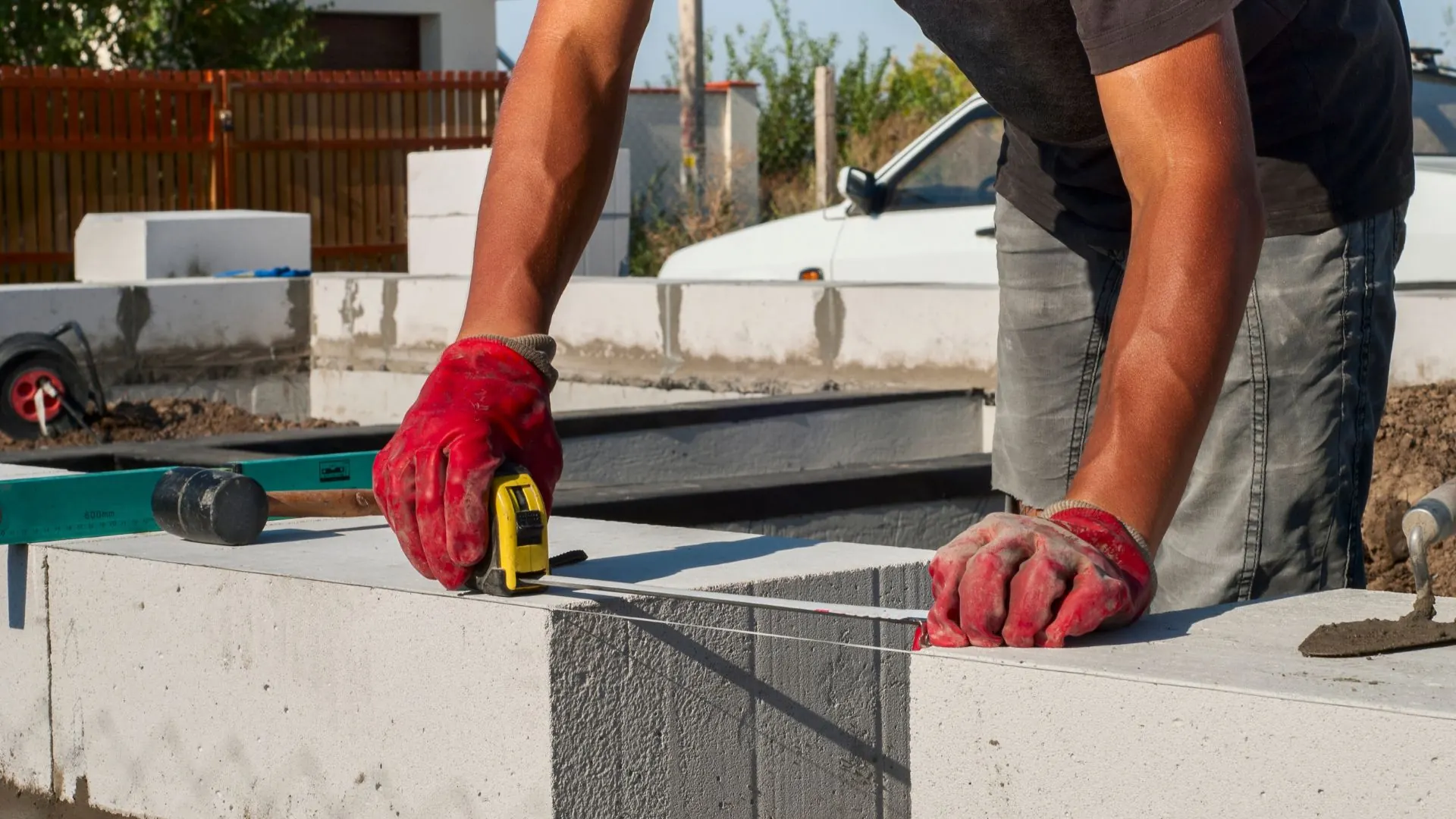 Maçon prenant la mesure d'un mur en blocs béton sur un chantier